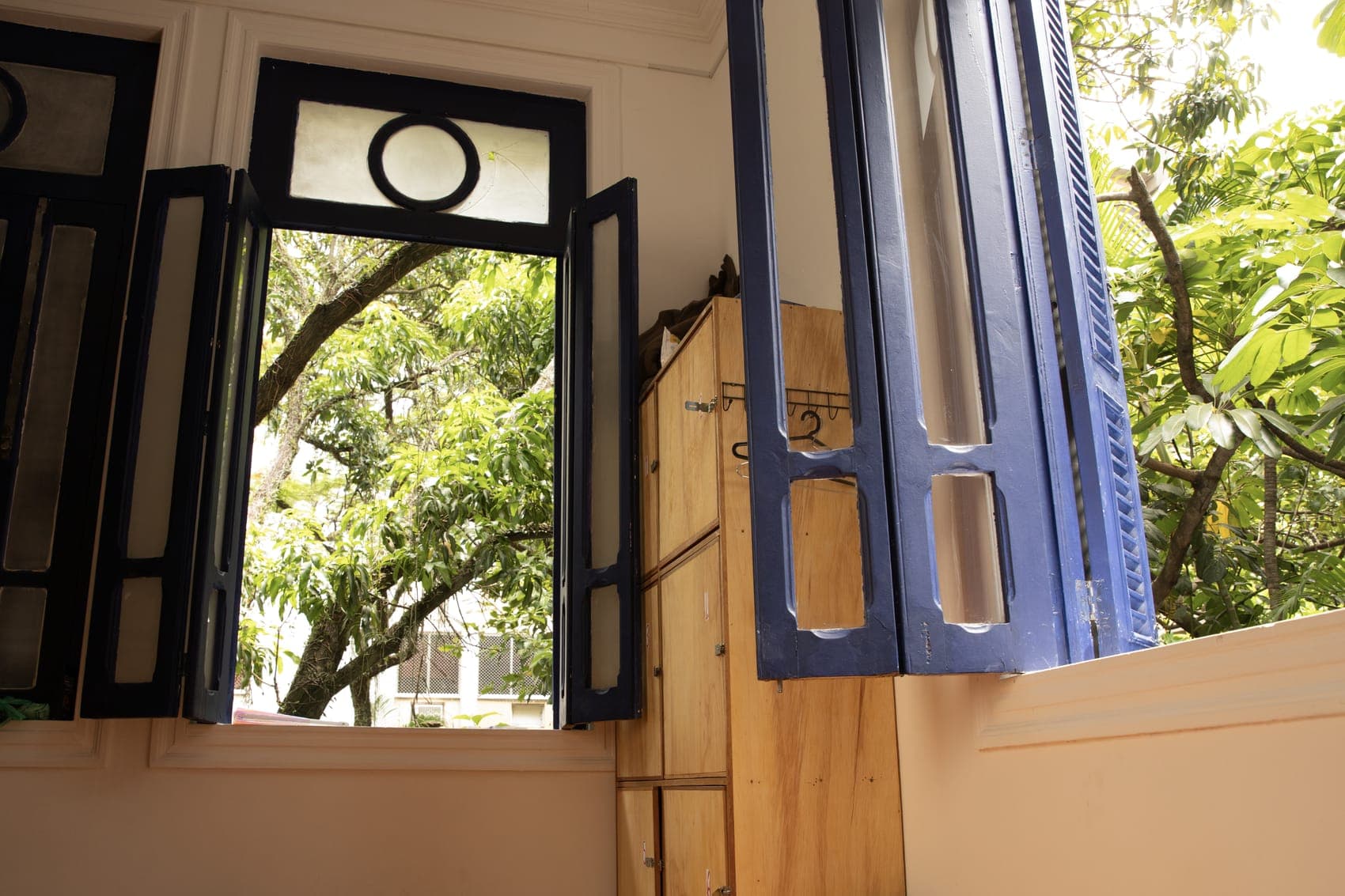 Bright dorm room with wooden lockers and blue-shuttered windows