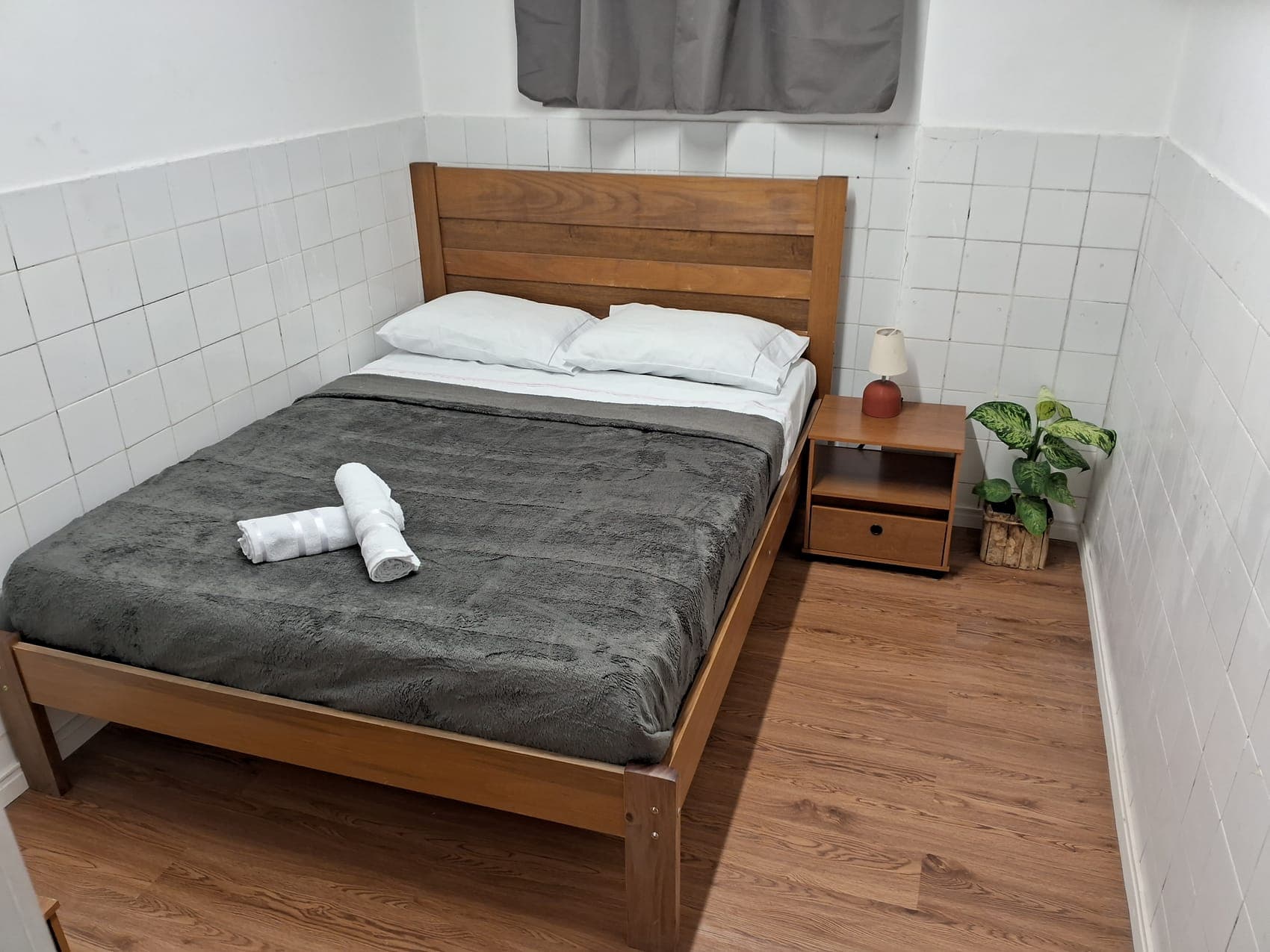 Budget private double room with a wooden bed, bedside table and fresh towels